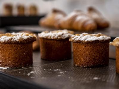 Baked pastries with powdered sugar, croissants in the background.